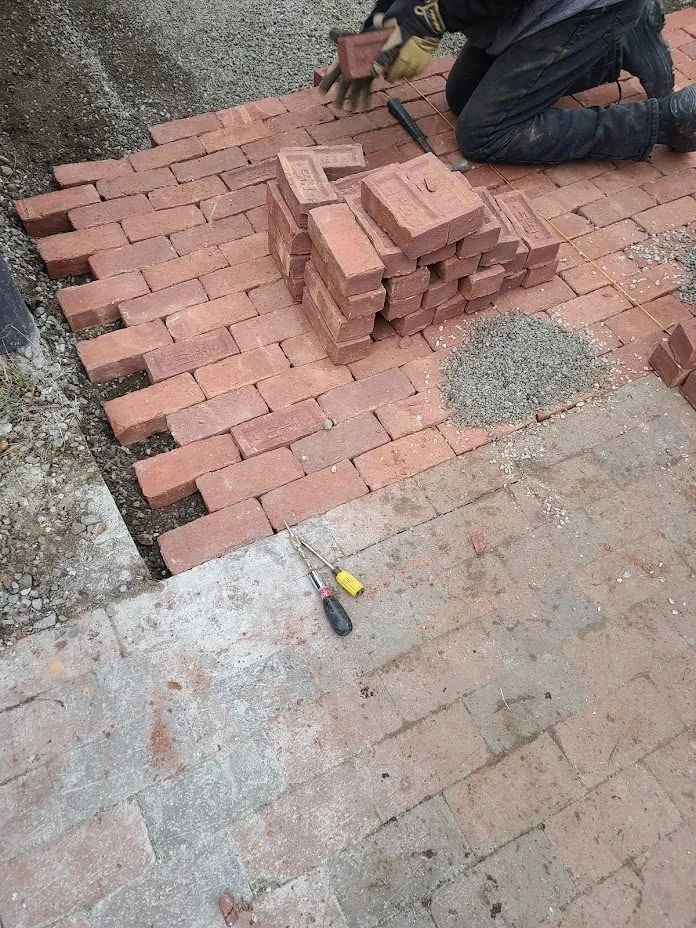 Brick pavers being installed in a herringbone pattern on a Boston patio project